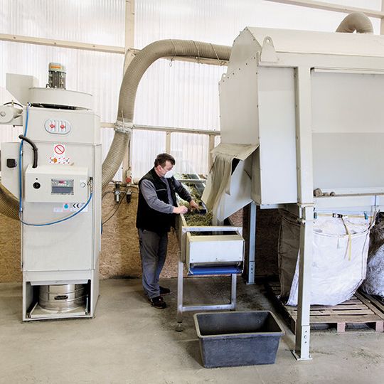 Die Siebmaschine (rechts im Bild) ist eingehaust und an einen Ruwac-Entstauber vom Typ DS 6 (links) angeschlossen.