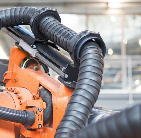 Rückzugsystem für E-ketten an Industrierobotern ermöglicht Führung von Zuführschläuchen für Nieten und Schrauben.