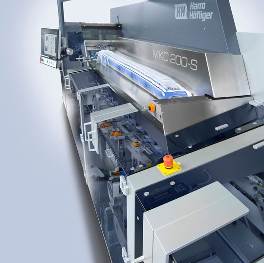 Wie bei den getakteten Kartoniermaschinen der Baureihe MKT ist Harro Höfliger bei MKC seinem Konzept mit Produkteinschub von hinten treu geblieben. Diese Lösung ermöglicht eine geradlinige Maschinenfront. Wie bei den getakteten Kartoniermaschinen der Baureihe MKT ist Harro Höfliger bei MKC seinem Konzept mit Produkteinschub von hinten treu geblieben. Diese Lösung ermöglicht eine geradlinige Maschinenfront.