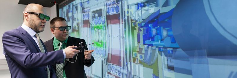 Dr. Stephan Tremmel (links), Oberingenieur am Lehrstuhl für Konstruktionstechnik und Projektleiter seitens der FAU, und FAU-Wissenschaftler David Hochrein verfolgen an der Powerwall die virtuelle Darstellung des Prüfstands.