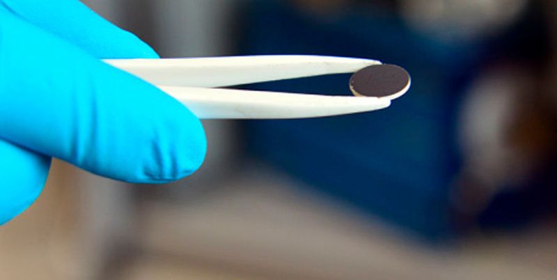 Eine Scheibe des (weissen) Lithiumgranat-Elektrolyten, beschichtet mit einer (schwarzen) Lithiumverbindung als Minuspol im Labor der ETH-Forschenden.