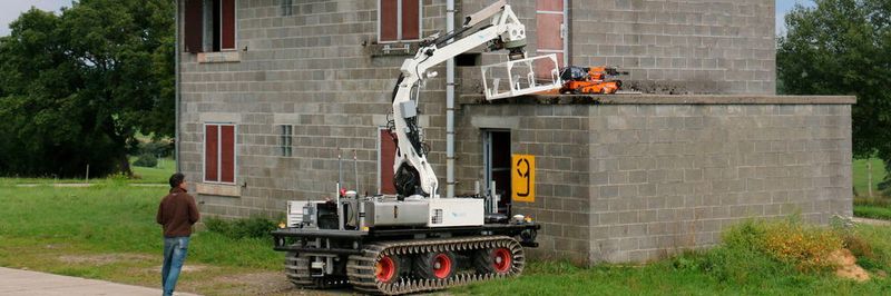 Der kleine Roboter SUGV wird während eines ICARUS-Projekt Tests von dem großen Roboter LUGV auf einem zerstörten Gebäude eingesetzt.