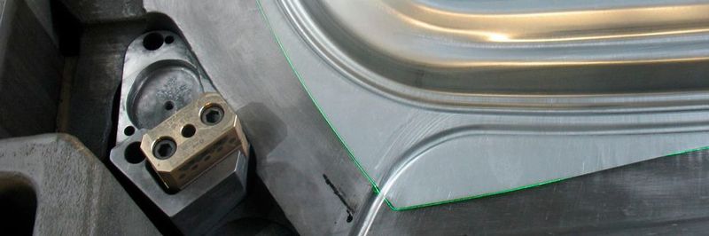 Auf dem Blechhalter liegendes Ziehteil mit projiziertem Blechkanteneinlauf (grüne Laserlinie).