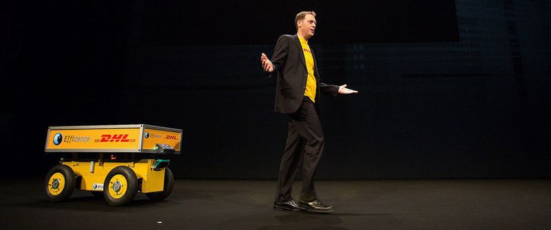 Dr. Markus Voss, DHL-CIO, mit dem Roboter-Rollwagen "Effibot" auf der Bühne des Fujitsu Forum in München