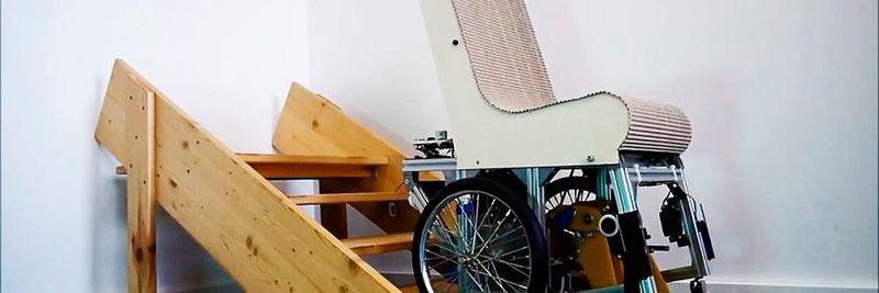 Ein Demonstrator-Modell des Assist Mobil während des Treppensteigens; die Beine befinden sich unterhalb des Rollstuhls und schieben ihn von Stufe zu Stufe.
