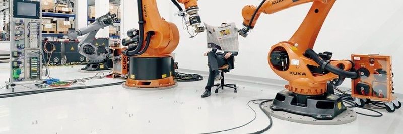 Klug inszeniert: Kuka-Roboter halten CEO Till Reuter die Zeitung.