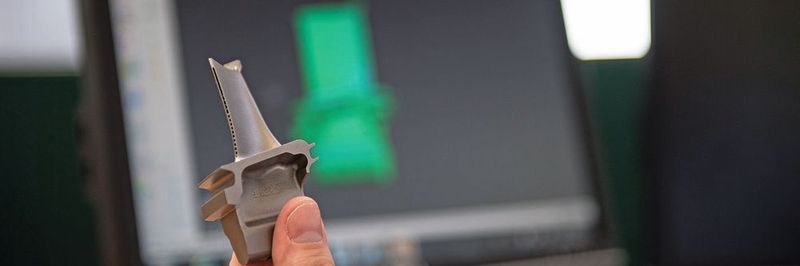 Die erste generativ gefertigte Turbinenschaufel «SGT400 Stage 1» (im Hintergrund die NX-Software) wurde von Materials Solutions, einem Siemens-Service-Provider für die additive Fertigung, produziert.