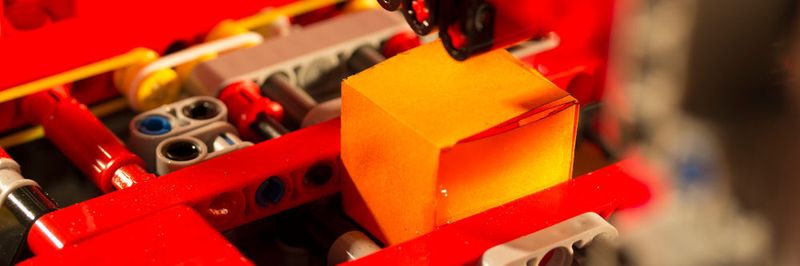 Mithilfe der Lego Mindstorms Technologie schneidet, faltet und klebt die Papercube-Anlage aus einem Stück Papier vollautomatisch einen Würfel.