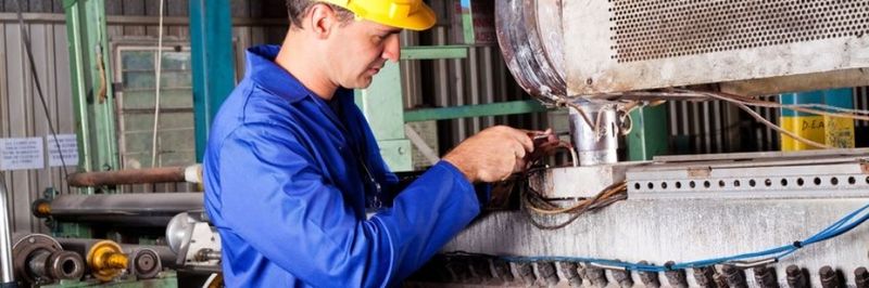 Industrial mechanic repairing heavy industry machine in plant