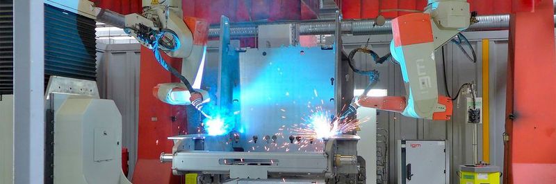 In der igm-Schweißzelle in Degernpoint schweißen zwei igm-Roboter gleichzeitig einen Fahrzeugrahmen. Damit stets in der qualitätssichernden Wannenlage geschweißt wird, ist der igm-Manipulator bei diesem Großteil zusätzlich mit einem Höhenfahrwerk ausgerüstet.