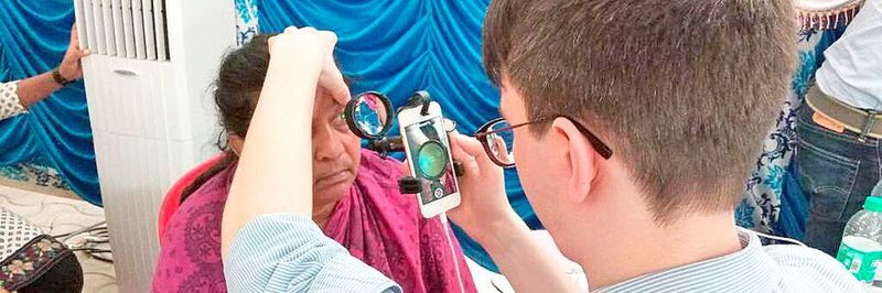 Dr. Maximilian Wintergerst untersucht das Auge einer Patientin mit einer indirekten Smartphone-Lösung