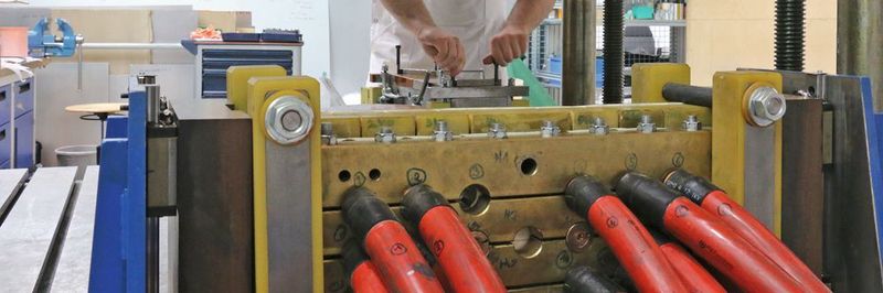 Der Aufbau zur inkrementellen elektromagnetischen Umformung mit Werkzeug (oben) und Stromspulen (unten).
