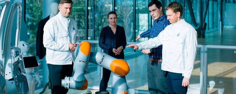 Sachsens Ministerpräsident Michael Kretschmer (rechts) probiert in der Gläsernen Manufaktur von Volkswagen in Dresden die neue Sensorjacke von Wandelbots aus.
