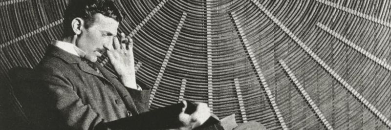 Nikola Tesla vor einer Spiralspule, die er für seine Experimente verwendete. Dieses Foto wurde erstmals 1896 in der Zeitschrift Electrical Review veröffentlicht.