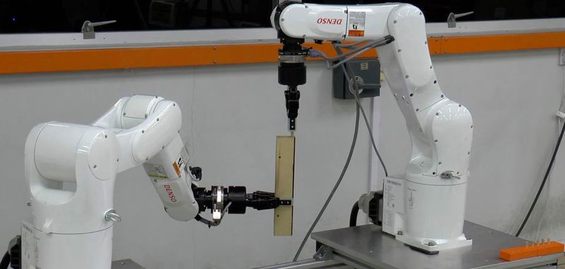 Zwei Roboterarme bauen einen Ikea-Stuhl zusammen und setzen dafür die Dübel ein. Das Bild zeigt einen frühen Versuchsaufbau von 2015.