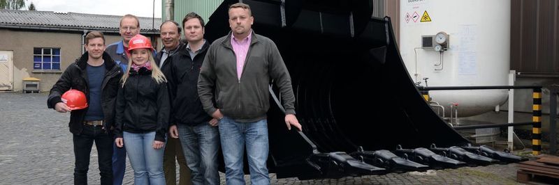 Nicht alle Schaufeln und Greifer von L&K sind so groß wie diese – aber alle zeichnen sich durch extreme Belastbarkeit und hohe Lebensdauer aus. Zweiter von rechts: Konstrukteur Roland Georgi. Dritter von rechts: Wolfgang Anderle, geschäftsführender Gesellschafter von L&K.