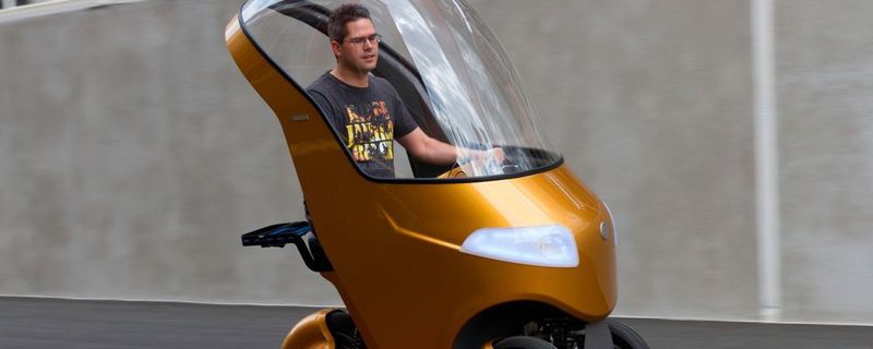 Das kleine Elektro-Dreirad schützt seinen Fahrer vor Wind und Wetter.
