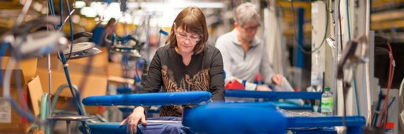 Erneuerte Beleuchtung und Ventilation an den Arbeitsstationen in der Bügelei sparen Energie, verbessern aber auch die Arbeitsqualität für Mitarbeiter.