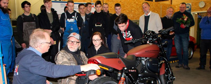 Die Harley-Davidson Street Rod mit (v. li.) Ferdinand Schütt, Björn Andersson, Azubis Celine Schneidereit und Nicklas Blome. Dahinter im weißen Jackett: Matthias Links.