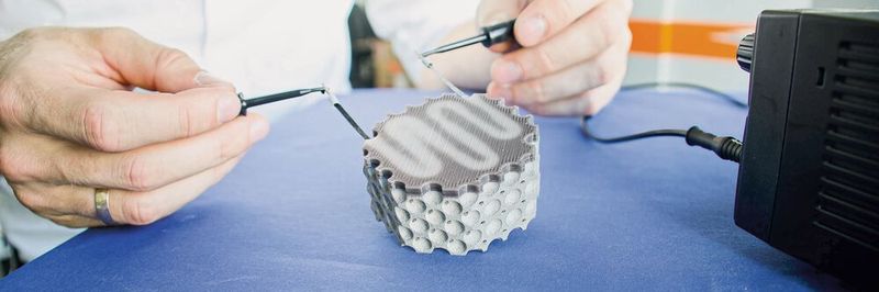 Der 3D-gedruckte Multi-Material-Leichtbaudemonstrator besteht aus kohlenstofffaserverstärktem thermochromem Kunststoff und Titan-Grundstruktur. Durch elektrische Aktivierung wird Wärme in der Kohlenstofffaser induziert und ein Farbwechsel im Kunststoff herbeigeführt.