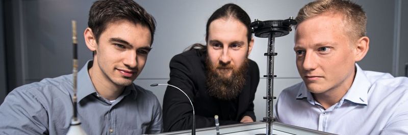 Die Doktoranden Dominik Scholtes (l.), Rouven Britz und Yannik Goergen (r.) aus Prof. Stefan Seeleckes Team mit Prototypen der biegsamen Roboterarme, die auf der Hannover Messe zu sehen sein werden.