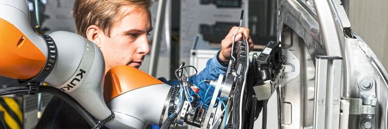 Sinnvolle Arbeitsteilung: Der Roboter trägt die Last und reicht an, der Werker unterstützt ihn beim passgenauen Einsetzen eines Bauteils.