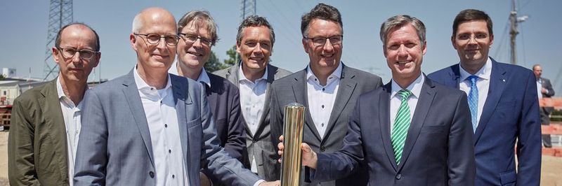 Beim versenken der Zeitkapsel (v.l.): Stefan Tebroke, Architekt von BHBVT, Dr. Peter Tschentscher, erster Bürgermeister der Hansestadt Hamburg, Prof. Dr. Hendrik Brinksma, Präsident der TUHH, Christian Langfeld, Leiter Abteilung Bau der Fraunhofer-Gesellschaft, Prof. Dr.-Ing. Uwe Clausen, Leiter Fraunhofer-IML, Prof. Dr. Ing. Carlos Jahn, Leiter Fraunhofer-CML sowie Ole John, Baubeauftragter des Fraunhofer-CML.