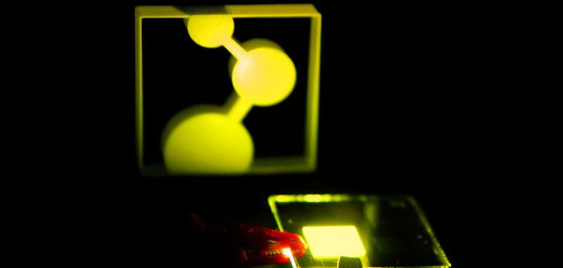 Der erste Prototyp der in Mainz entwickelten OLED beleuchtet das Logo des MPI-P. Die OLED besteht nur noch aus einer Schicht mit einem externen Wirkungsgrad von 19%.