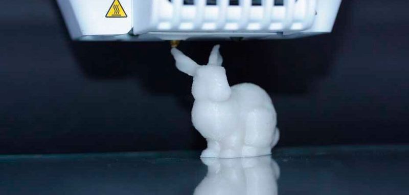 Ein 3D-Drucker druckt einen Kunststoffhasen. Im Kunststoff sind DNA-Moleküle enthalten, in denen die Druckanleitung kodiert ist.