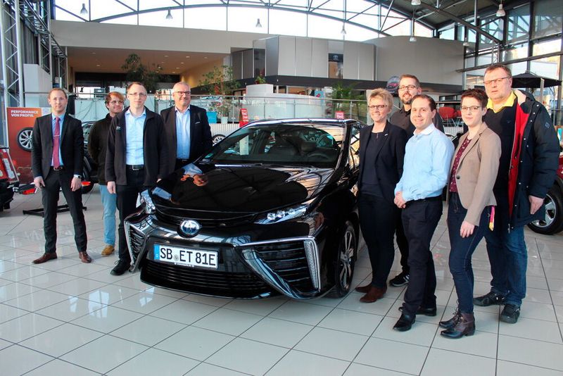 Eine Delegation der Forschungsgruppe Verkehrstelematik der Fakultät für Ingenieurswissenschaften mit dem Toyota Mirai, der ab sofort als Testfahrzeug fungiert.