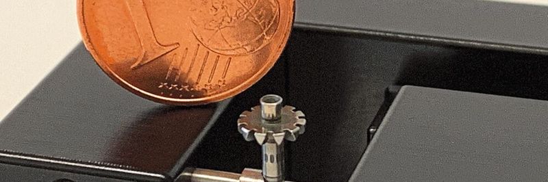 Im Vergleich mit einer Ein-Cent-Münze wird die Größenordnung der Prismenhalterung des Mikro-Reitstocks deutlich.