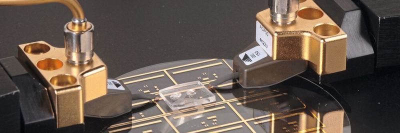 Die Goldlinien auf der Glasscheibe sind Mikrowellenübertragungsleitungen. Der 1,25 cm breite Polymerblock beherbergt eine Miniaturkammer, in der ein mikrolitergroßer Flüssigkeitstropfen erhitzt werden kann.