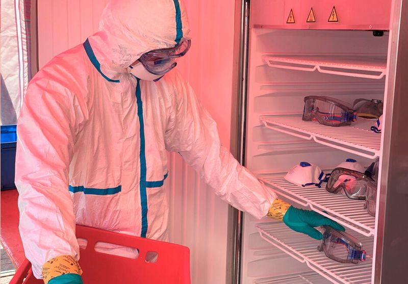 Benutzte Atemschutzmasken und Schutzbrillen werden von Lukas Krapf von der Bayerisches-Rotes-Kreuz-Schnelleinsatzgruppe CBRN(E) zur Wiederaufbereitung in die Anlage gelegt.