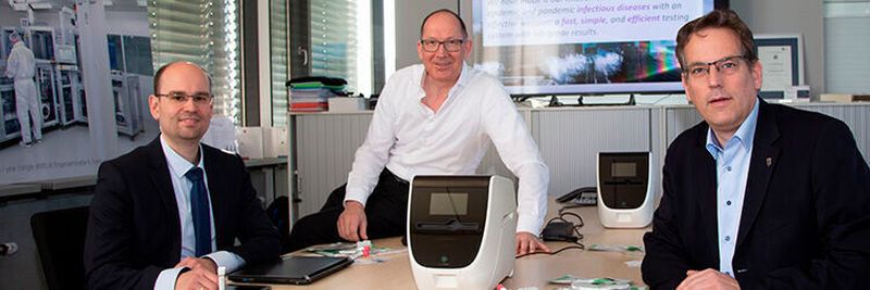 Professor Erik Schweickert MdL (ganz rechts) machte sich bei Hahn-Schickard selbst ein Bild vom Testsystem, das nun für den Corona-Nachweis weiterentwickelt wird. Dr. Daniel Mark von Spindiag (li.) und Hahn-Schickard-Institutsleiter Professor Roland Zengerle führten das System vor
