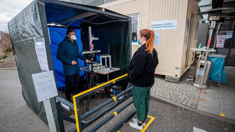 Dr. Urs Schneider vom Fraunhofer IPA misst bei einer Probandin. Das Messsystem besteht aus einer Thermokamera und misst die Körpertemperatur sowie einem Radar, um Herz- und Atemfrequenz zu messen.