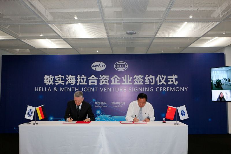 Didier Keskas (links), bei Hella verantwortlich für das Lichtgeschäft in Asien, und Yanchun Liu, Chief Operating Officer der Minth Group, unterzeichnen die Vereinbarung zur Gründung des Joint Ventures.