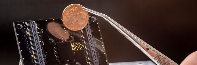 Digitale Spürnase: Der an der TU Graz entwickelte Prototyp des Partikelsensors (das schwarze Quadrat in der Mitte der Platine) im Größenvergleich mit einer Ein-Cent-Münze.