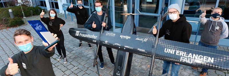 Team TechFak EcoCar mit dem Pokal für den 1. Platz beim NFC 2020 und dem elektrischen VTOL-Copter "Night Fury".
