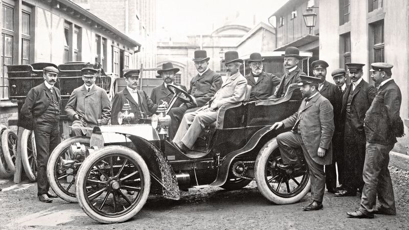 Wilhelm Maybach, vorn auf dem Beifahrersitz eines Mercedes-Simplex 18/22 PS im Jahr 1903 im Fabrikhof des Cannstatter Werks der Daimler-Motoren-Gesellschaft. Er gilt als einer der größten Erfinder im Automobil- bzw. Motorenbau.