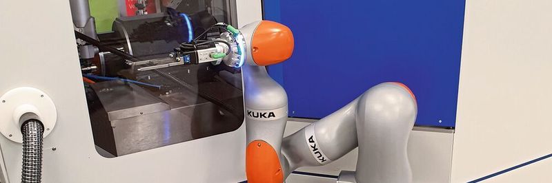 Der Roboterarm holt vorbereitete Werkstücke vom Palettenwagen im Vordergrund und macht den automatischen Werkstückwechsel.