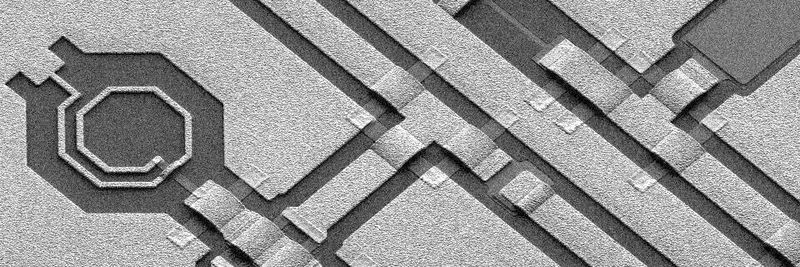 Die REM-Aufnahme zeigt einen Ausschnit eines rauscharmen Verstärkers in einem GaN-MMIC (links vier Spulen, rechts ein Transistor).