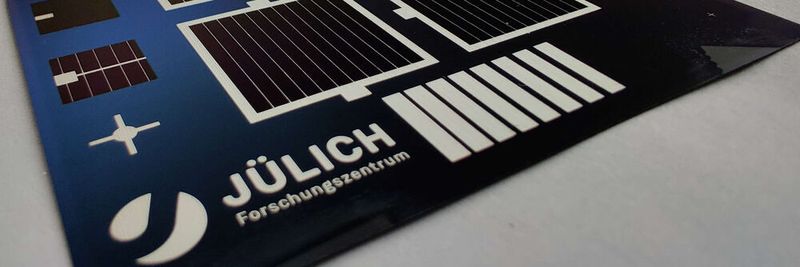Prototyp der fertigen Solarzellen in Laborgröße (TPC - Transparent Passivating Contact). Auf dem Siliziumwafer sind vier jeweils vier Quadratzentimeter große Solarzellen zu sehen, die jeweils mit siebgedruckten Silberkontakten kontaktiert und eingerahmt sind.