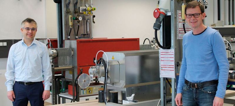 Prof. Dr.-Ing. Stefan Schafföner (li.) und PD Dr. Günter Motz (re.) vor dem Ofen für die Herstellung der Carbonfasern bei 1400 Grad Celsius.