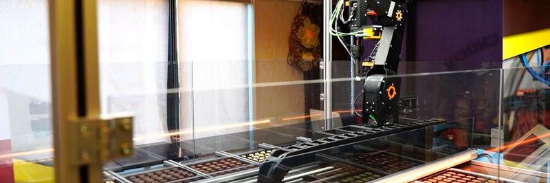 Der Chocomatic von Roose Automation ist ein echter Hingucker im Verkaufsbereich. Der Kunde steuert mit einem Tablet oder dem eigenen Smartphone einen Roboter, der aus einer Palette unterschiedlicher Pralinen individuell für den Kunden auswählt.