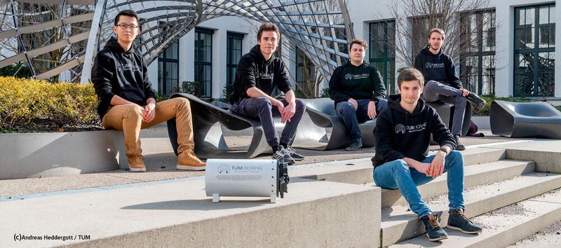Die Projektleiter des TUM Boring Teams auf der Treppe der TU München mit dem Modell der Tunnelbohrmaschine. Von links nach rechts: Haokun Zheng, Elias Schmid, Max Herbst, Kilian Schmid, Marvin von Hagen.
