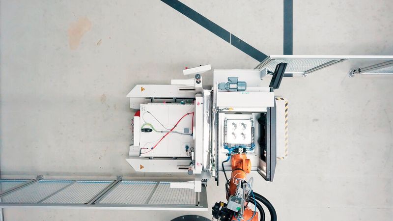 Ein Roboter entnimmt die additiv gefertigten Bauteile von der Bauplattform.