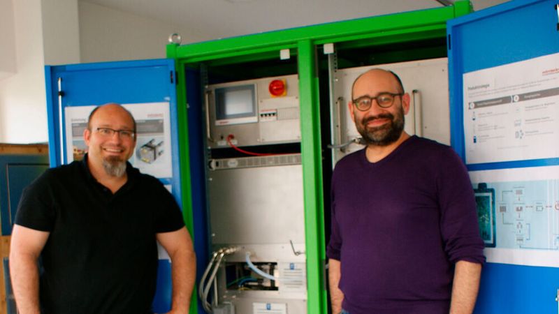 Peter (links) und Markus Ostermeier stehen vor ihrer Anlage, die mittels Elektrolyse von Wasser und Grünstrom als Energiespeicher funktioniert.