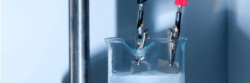 An metallischen Netzen wird Wasser elektrochemisch zu Wasserstoff und Sauerstoff gespalten, welche als Gasblasen entweichen.