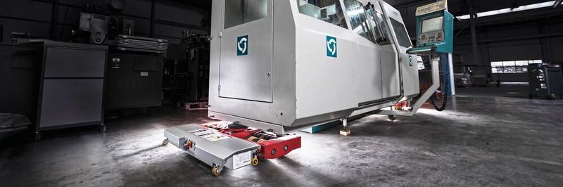 Ein Fräsmaschinenzentrum von Reckermann wird mithilfe eines elektrischen Schwerlast-Fahrwerks „JLA-e“ in einer Werkshalle in Position gebracht.