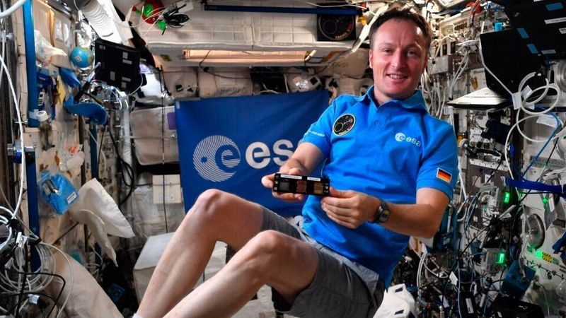 Matthias Maurer auf der ISS mit Materialproben, deren neuartige Oberflächen einen Bakterienbefall minimieren sollen.